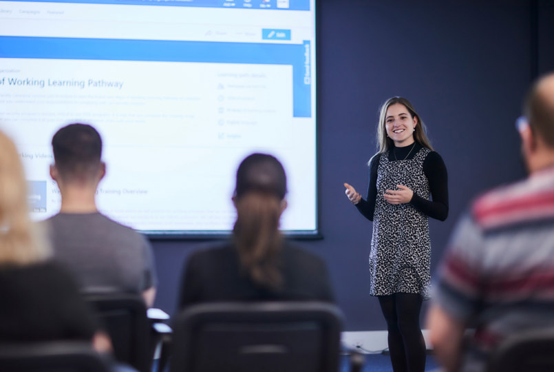 Employee presenting in front of a room of colleagues 