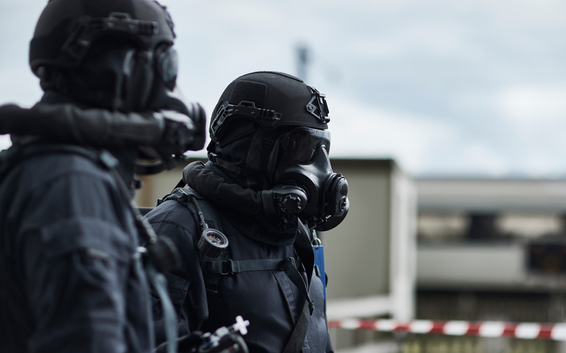 Two soldiers on staircase wearing ballistic helmets and respirators